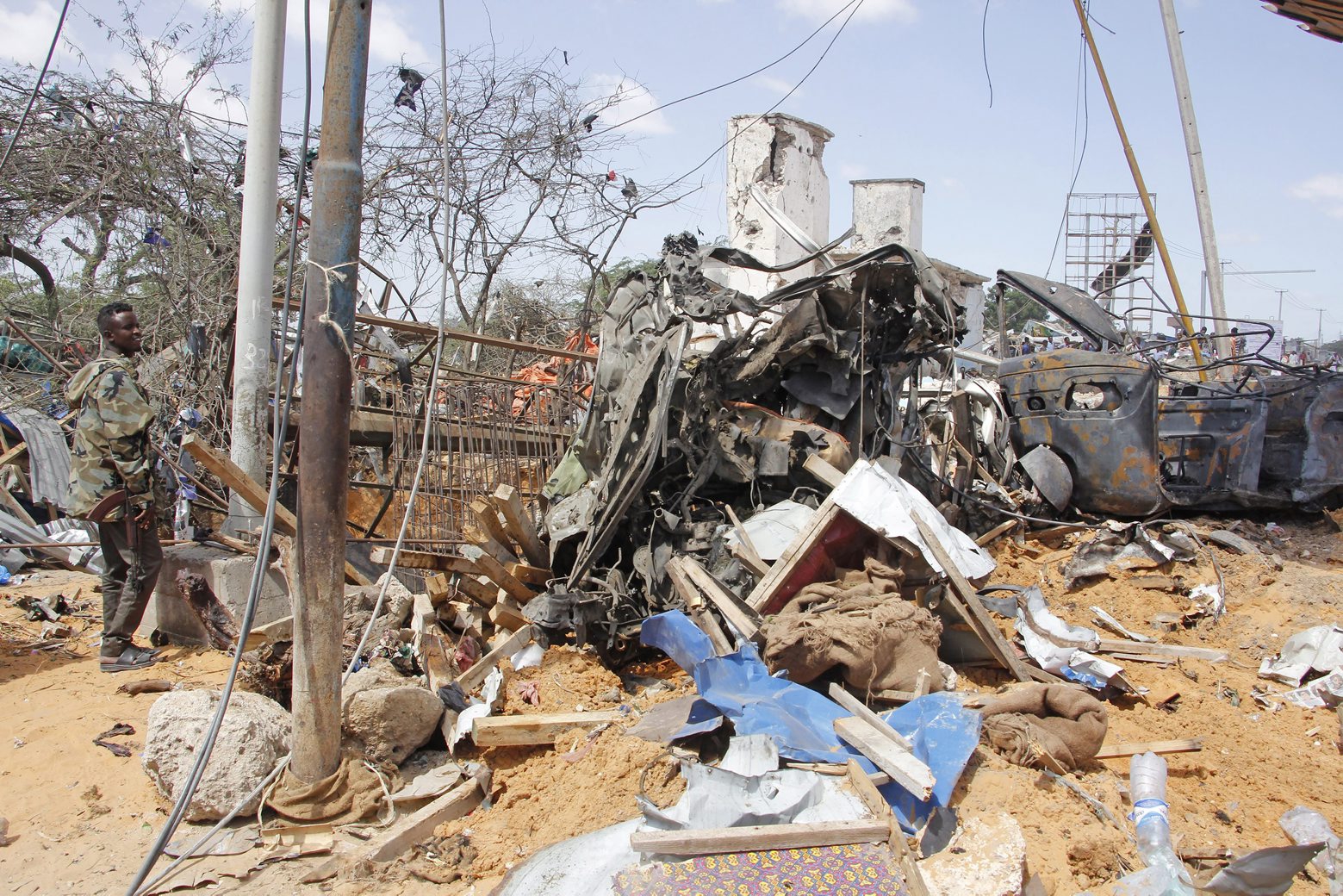 A soldier stands guard near wreckage of vehicles in Mogadishu after a car bomb in Mogadishu, Somalia, Saturday, Dec. 28, 2019. A truck bomb exploded at a busy security checkpoint in Somalia's capital Saturday morning, authorities said. It was one of the deadliest attacks in Mogadishu in recent memory. (AP Photo/Farah Abdi Warsame) Somalia Blast