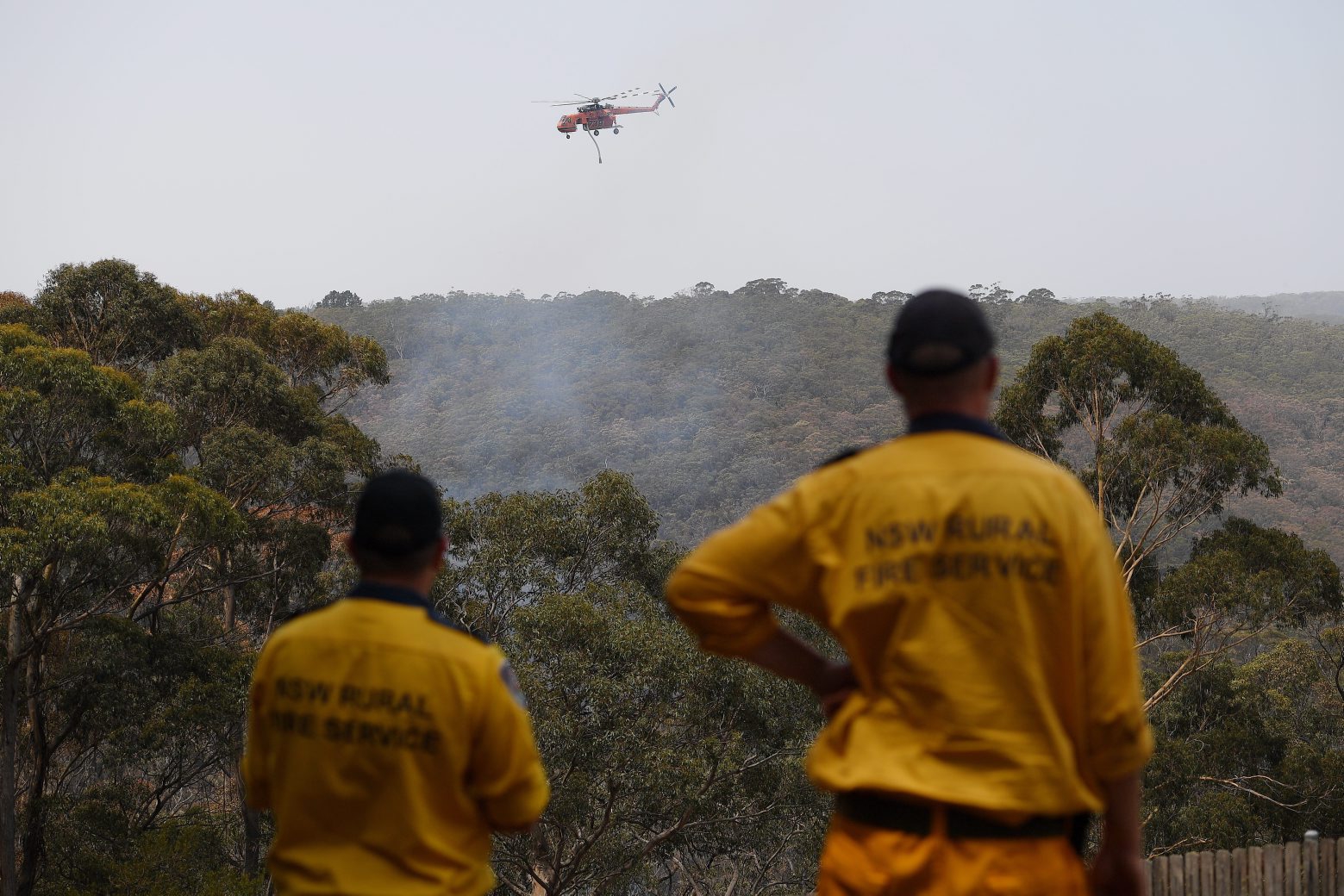 epa08115790 New South Wales Rural Fire Service crews watch as water bombing helicopters fight a fire burning in bushland at Penrose, New South Wales, Australia, 10 January 2020. The Rural Fire Service has placed total fire bans on 10 regions across the state.  EPA/DAN HIMBRECHTS AUSTRALIA AND NEW ZEALAND OUT AUSTRALIA BUSHFIRES NEW SOUTH WALES