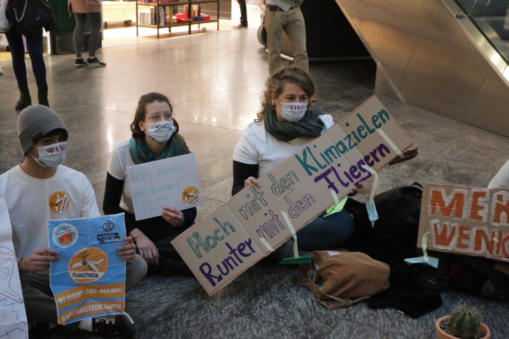Les militants portaient des masques et des pancartes tels que ceux-ci, où l'on peut lire "De meilleurs objectifs pour le climat / Moins de vols".