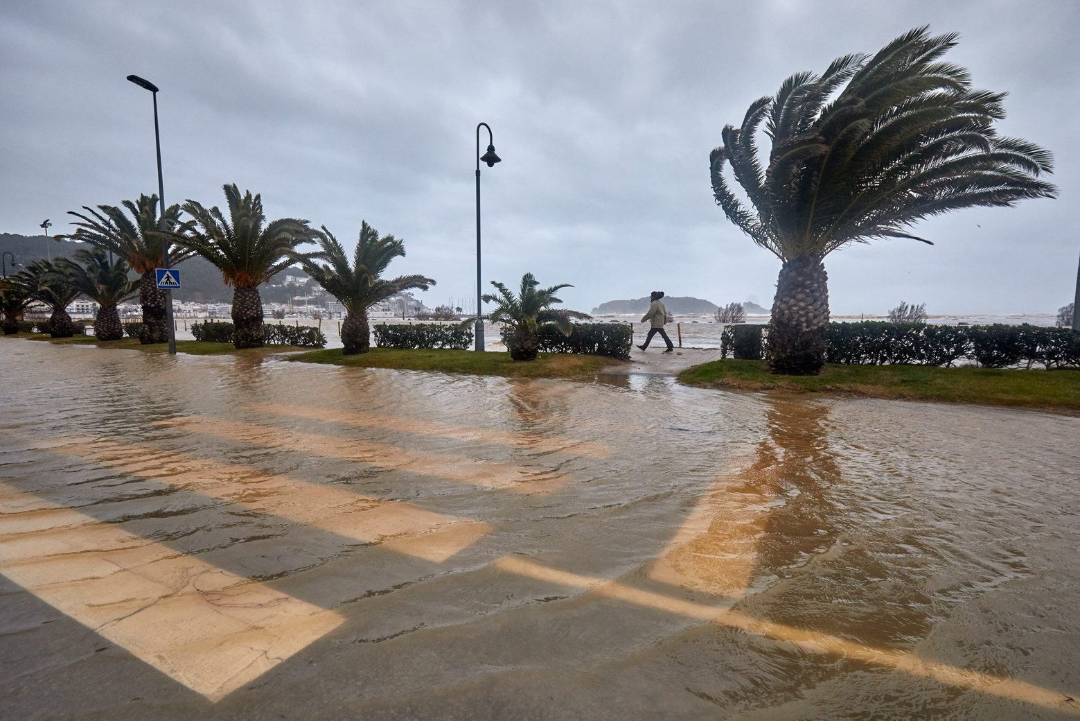 epa08147927 People pass by the seaside promenade of L'Estartit in Girona, Spain, 21 January 2020.  The low pressure Gloria hitting eastern Spain caused at least three deaths, while roads are blocked and reportedly more than 200,000 students left classless due to heavy rainfalls and storms.  EPA/DAVID BORAT SPAIN WEATHER