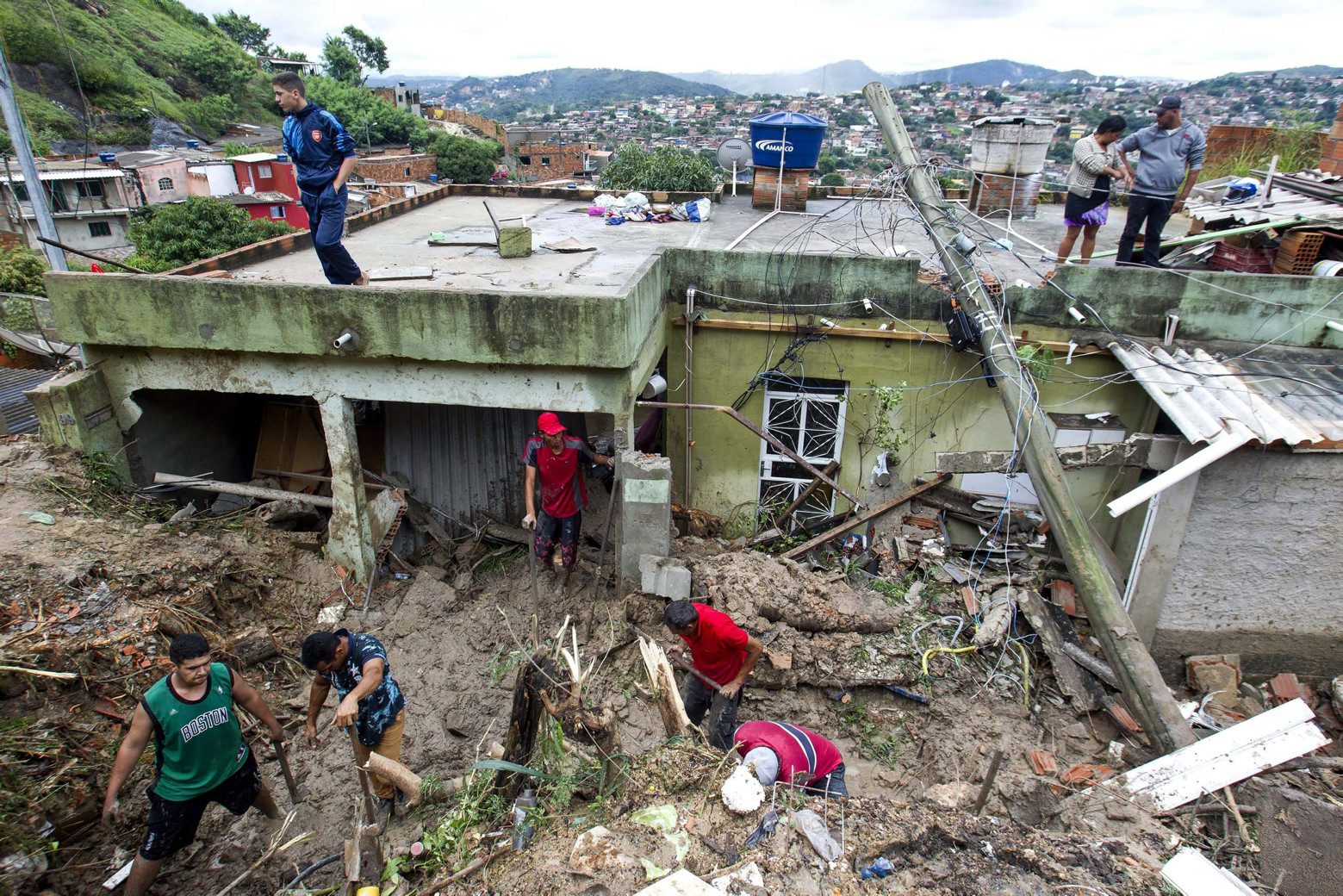Locals work to clean up mud and debris around houses destroyed by a landslide after heavy rains in Vila Ideal neighborhood, Ibirite municipality, Minas Gerias state, Brazil, Saturday, Jan.25, 2020. Heavy rains caused flooding and landslides in southeast Brazil, killing at least 30 people, authorities said Saturday. (AP Photo/Alexandre Mota-Futura Press) Brazil Heavy Rains