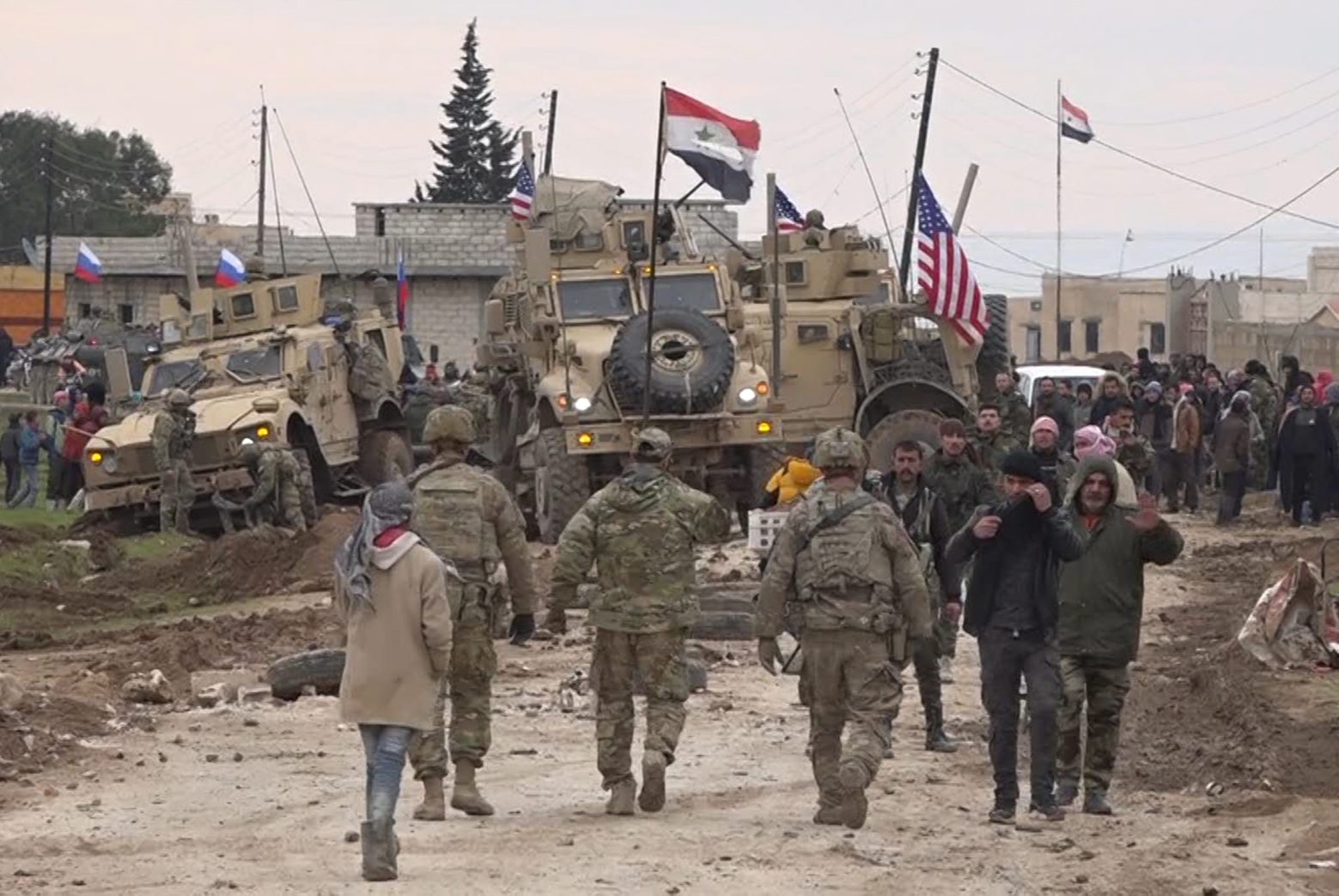 In this frame grab from video, Russian, Syrian and others gather next to an American military convoy stuck in the village of Khirbet Ammu, east of Qamishli city, Syria, Wednesday, Feb. 12, 2020. Syrian media and activists say a Syrian was killed and another wounded in a rare clash between American troops and a group of government supporters in northeast Syria. (AP Photo) Syria