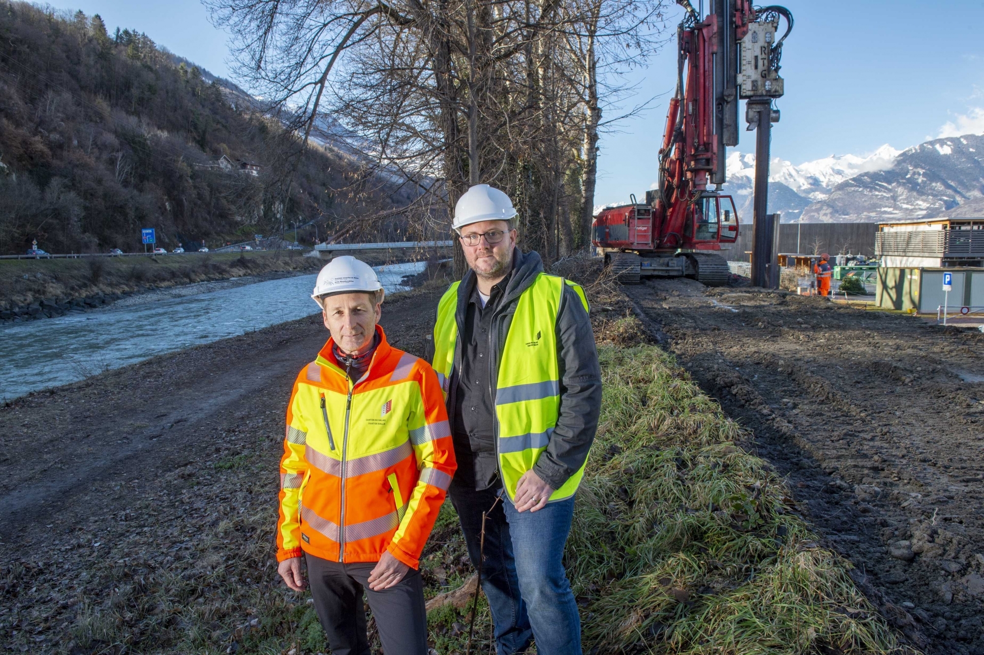 Toni Arborino, chef de l'Office cantonal de Rhône 3, et Didier Tille, responsable pour le Valais central, posent devant la machine qui enfonce les palplanches à l'intérieur de la digue existante. Ici, à la hauteur de la voirie de Sion.