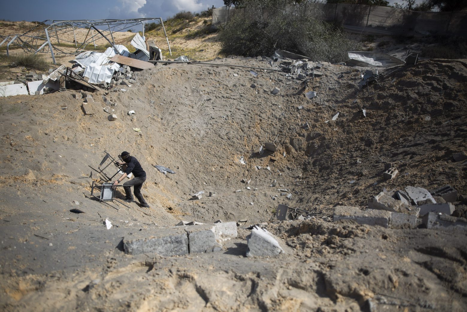 A masked Palestinian militant checks the damage following overnight Israeli airstrikes on an Islamic Jihad military base in the town of Khan Younis, Southern Gaza Strip, Monday, Feb. 24, 2020. (AP Photo/Khalil Hamra) Israel Palestinians