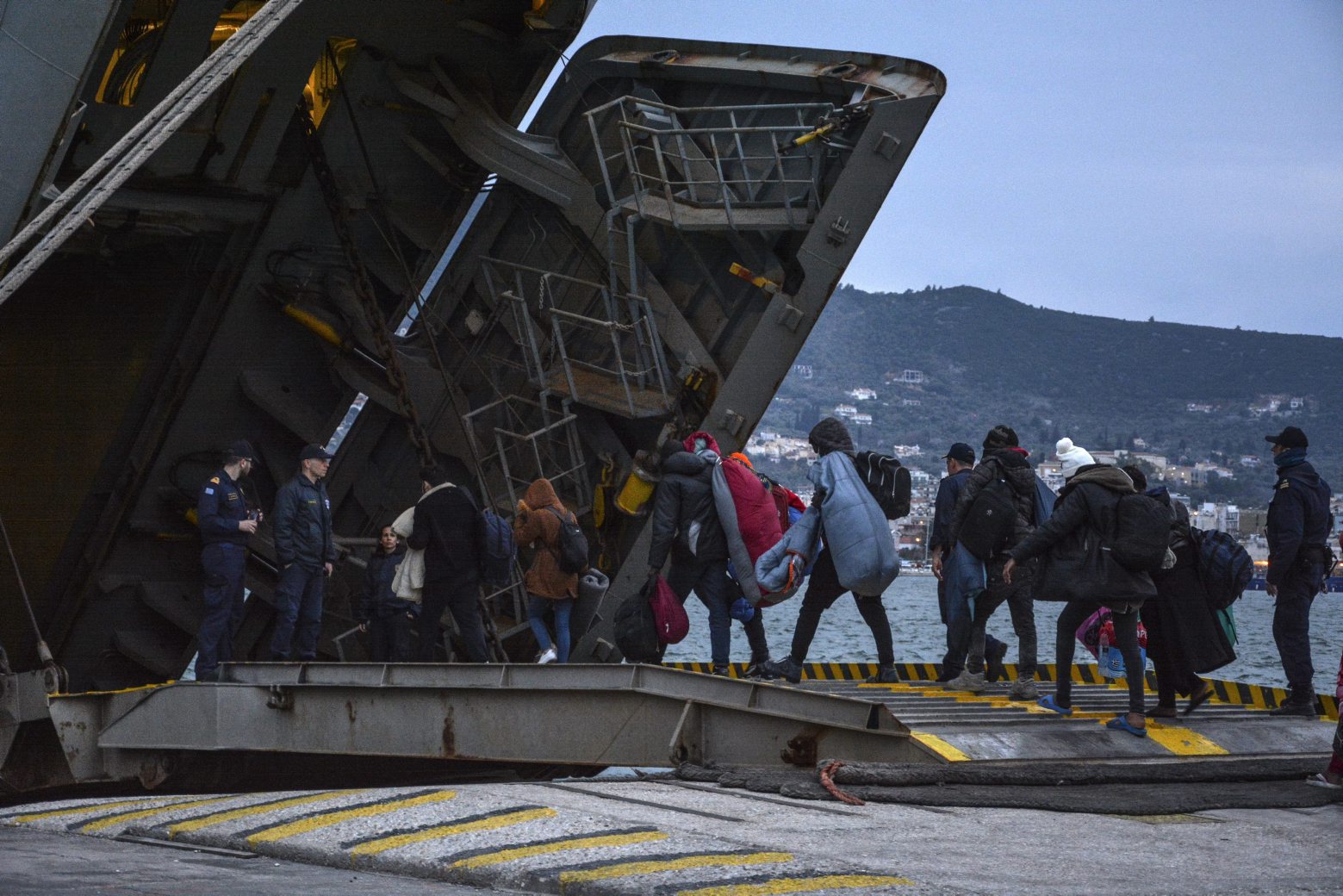 Migrants enter a Greek Navy ship which will accommodate them at the port of Mytilene on the northeastern Aegean island of Lesbos, Greece, on Wednesday, March 4, 2020. Turkey made good on a threat to open its borders and send migrants into Europe last week. In the past few days hundreds of people have headed to Greek islands from the nearby Turkish coast in dinghies. (AP Photo/Panagiotis Balaskas) Greece Turkey Migrants