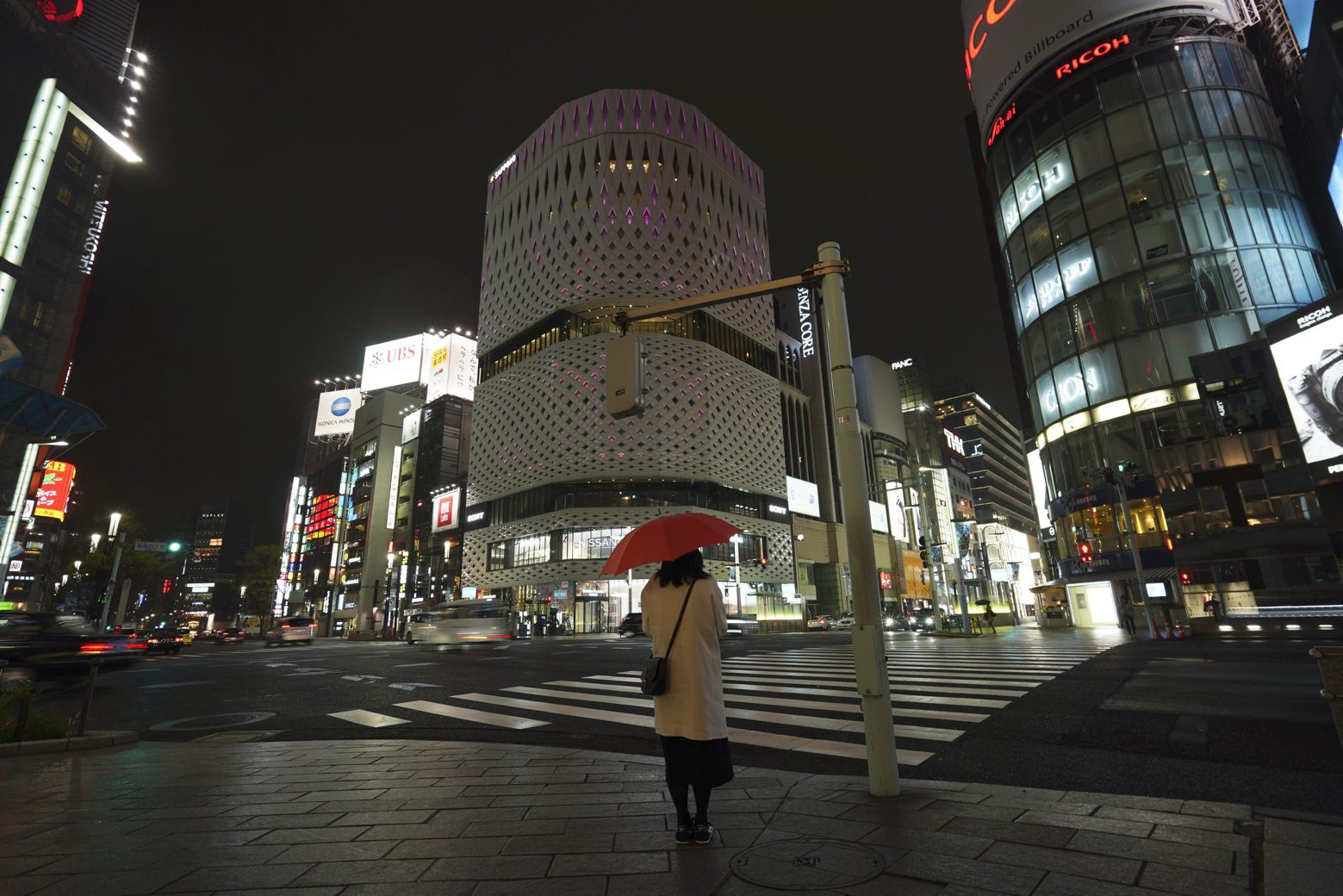FILE - In this March 28, 2020, file, photo, a woman stands at empty Ginza shopping district in Tokyo Saturday, March 28, 2020. Before the Olympics were postponed, Japan looked like it had coronavirus infections contained, even as they spread in neighboring countries. Now that the games have been pushed to next year, TokyoÄôs cases are spiking, and the city's governor is requesting that people stay home, even hinting at a possible lockdown. (AP Photo/Eugene Hoshiko, File) Virus Outbreak Japan Tokyo's Spike