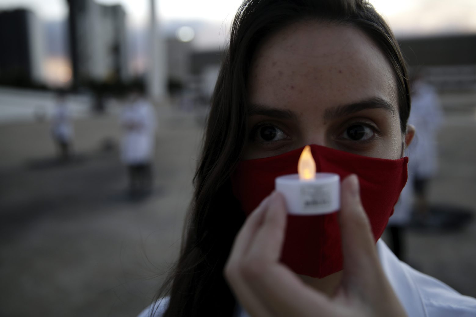A nurse holds an artificial candle in honor of a colleague who died fighting against the new coronavirus pandemic, during a protest marking International Nurses Day, in Brasilia, Brazil, Tuesday, May 12, 2020. (AP Photo/Eraldo Peres) Virus Outbreak Brazil