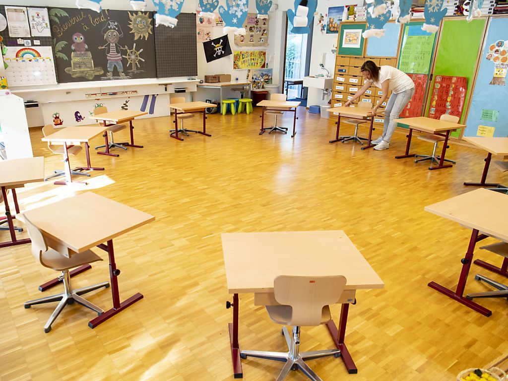 L'enseignante prépare sa classe en espaçant les tables.