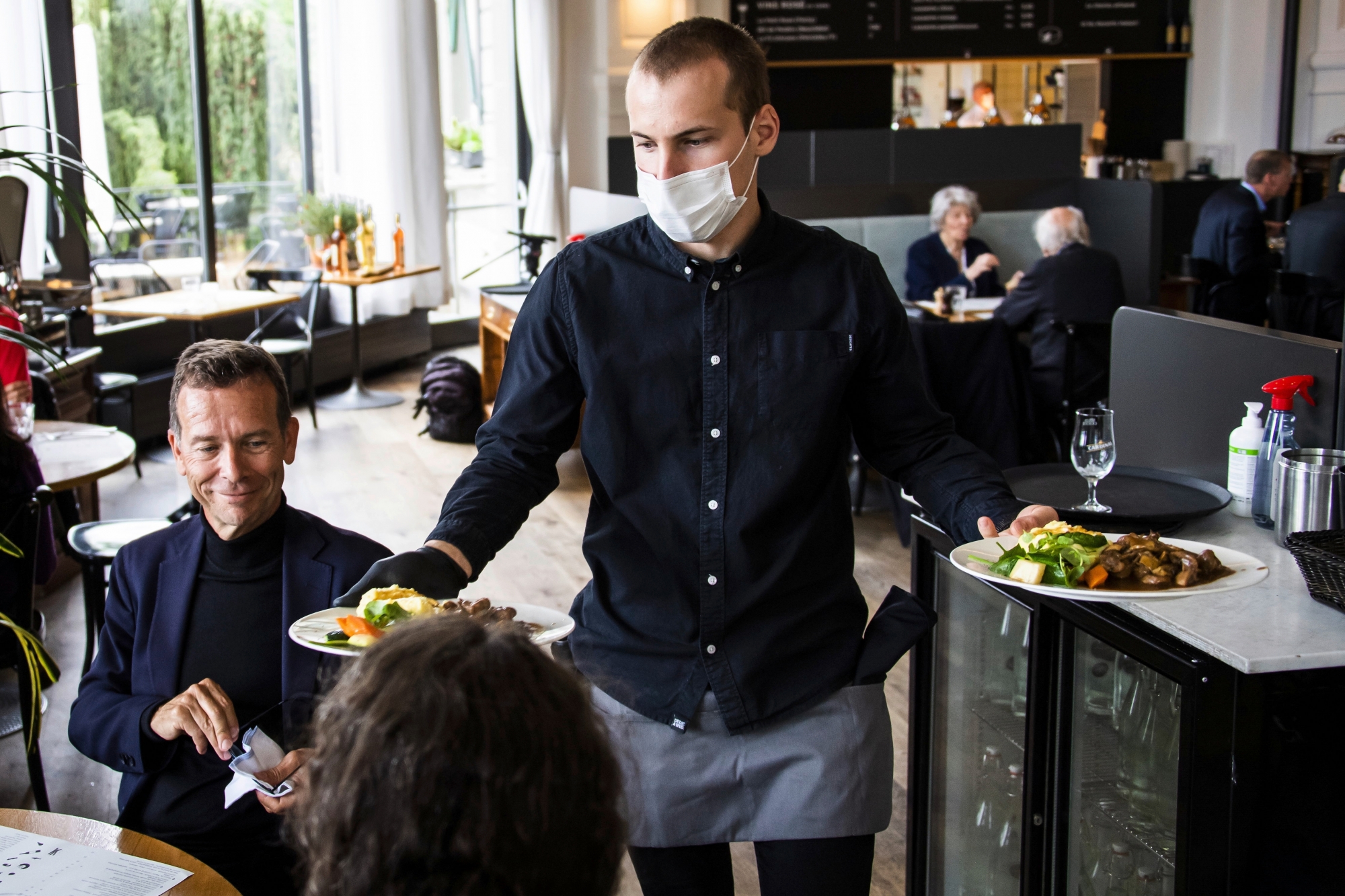 A waiter of "La Brasserie de Montbenon" restaurant brings dishes food to customers during the spread of the pandemic Coronavirus (COVID-19) disease in Lausanne, Switzerland, Monday, May 11, 2020. In Switzerland from today, the Swiss authorities lifted second part of the lockdown. (KEYSTONE/Jean-Christophe Bott)
ArcInfo
