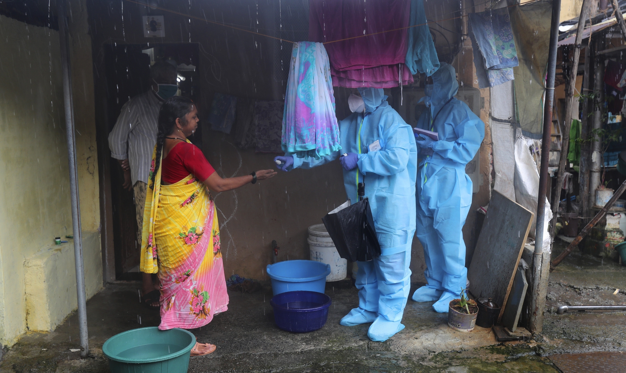 Health workers screen people for COVID-19 symptoms at a slum in Mumbai, India, Tuesday, July 14, 2020. Several Indian states imposed weekend curfews and locked down high-risk areas as the number of coronavirus cases surged past 900,000 on Tuesday. (AP Photo/Rafiq Maqbool) ArcInfo
