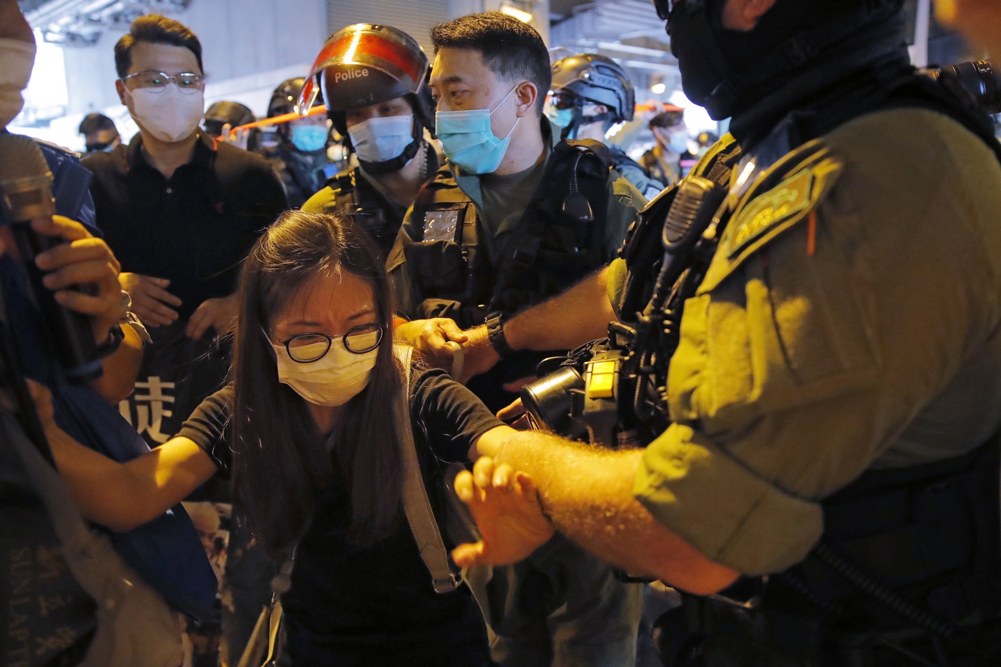 Pro-democracy protesters, front left and rear left, are surrounded by riot police during a news conference to mark one-year anniversary of the Yuen Long subway attack at the subway station in Hong Kong, Tuesday, July 21, 2020. A gang of men in white shirts brutally beat dozens of people inside the train station on July 21 last year. (AP Photo/Kin Cheung) ArcInfo