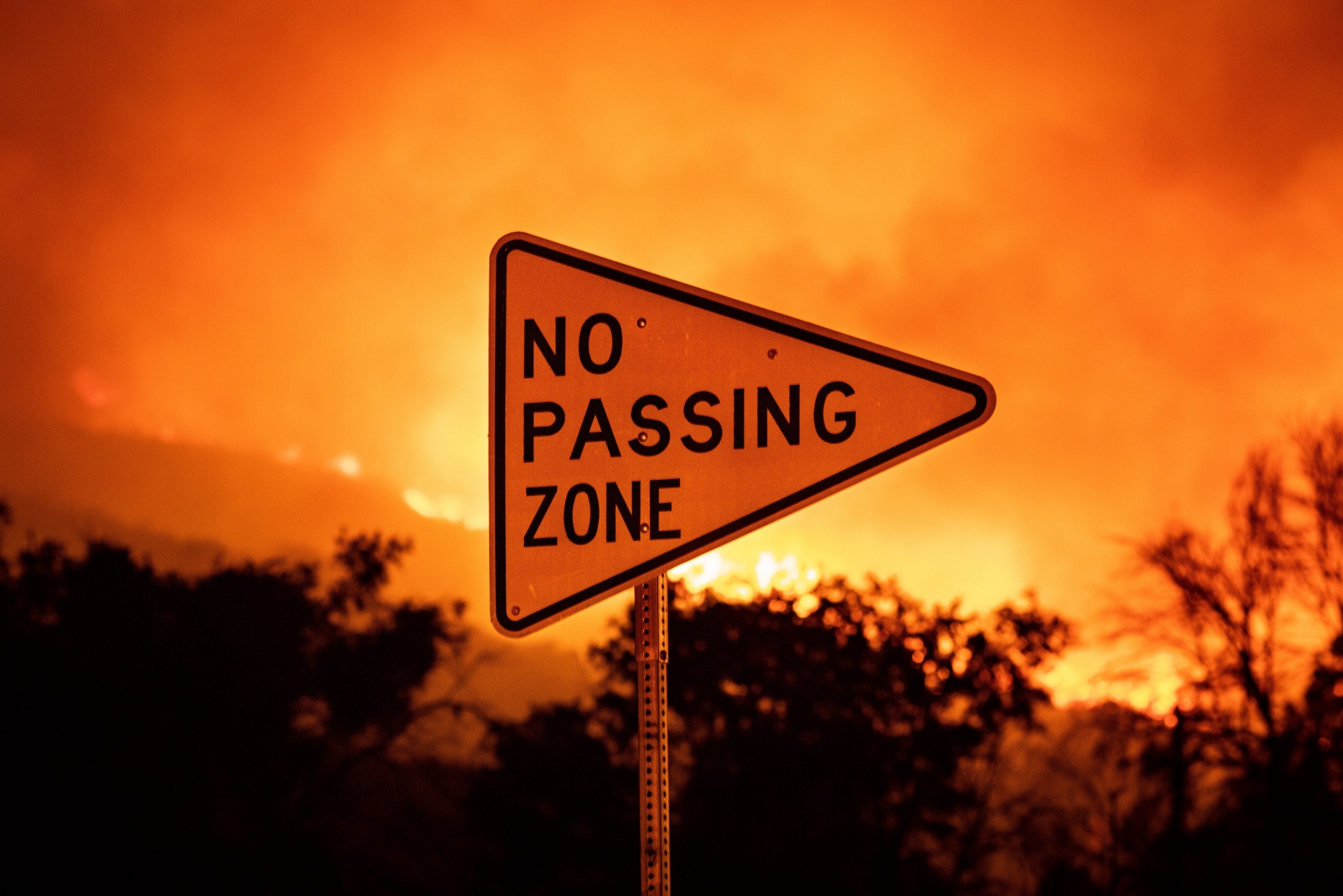 epa08600313 A no passing zone sign is seen with flames behind it at the Lake Fire in Lake Hughes, California, USA, 12 August 2020.  EPA/CHRISTIAN MONTERROSA ArcInfo