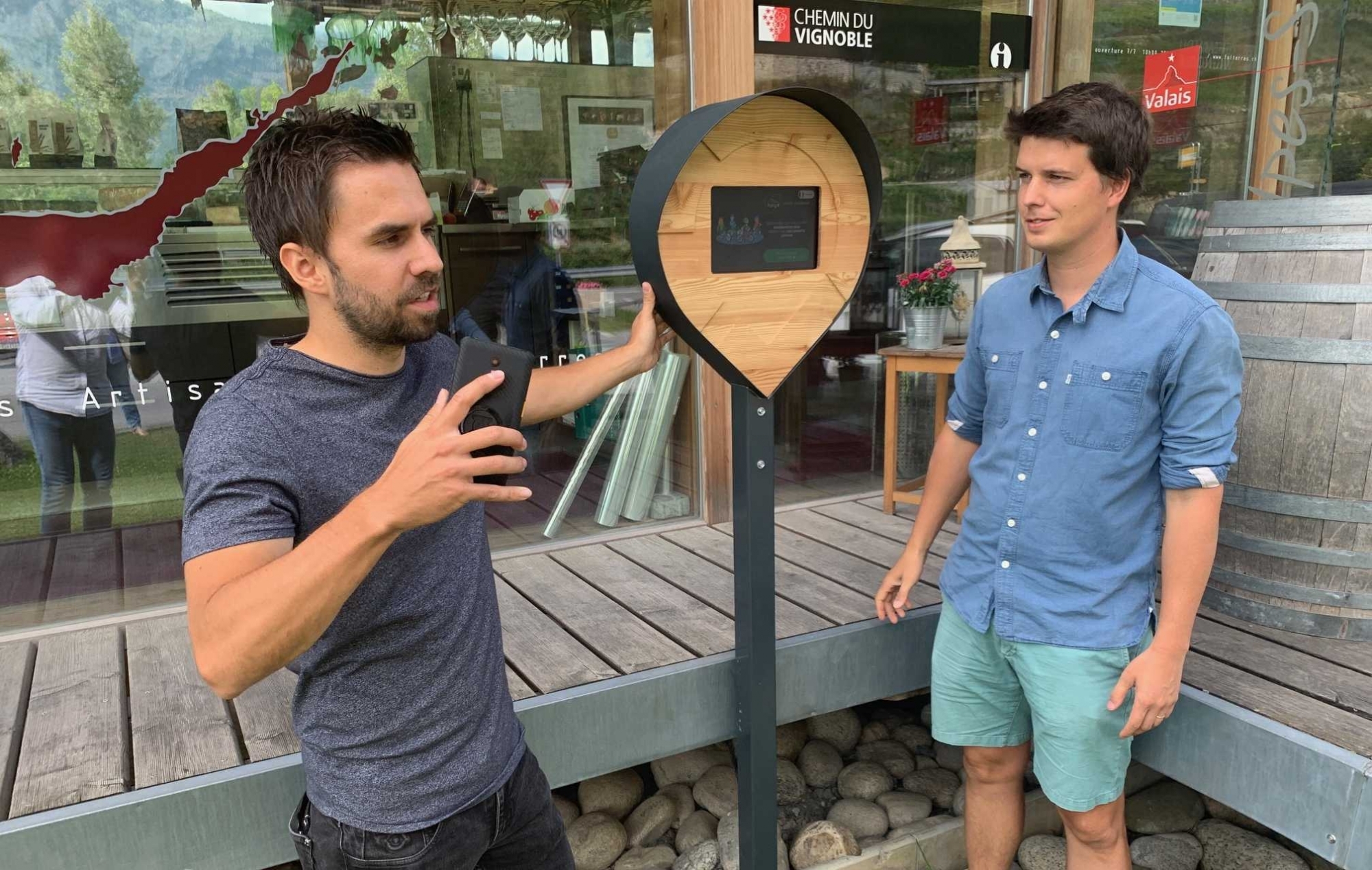 Baptiste Roduit, représentant de la société Guidos, et Alexandre Roduit, directeur de Fully Tourisme, présentent la borne fraîchement posée devant le Pavillon agritouristique des Fol’terres pour guider les amateurs de vélo, électrique ou pas.